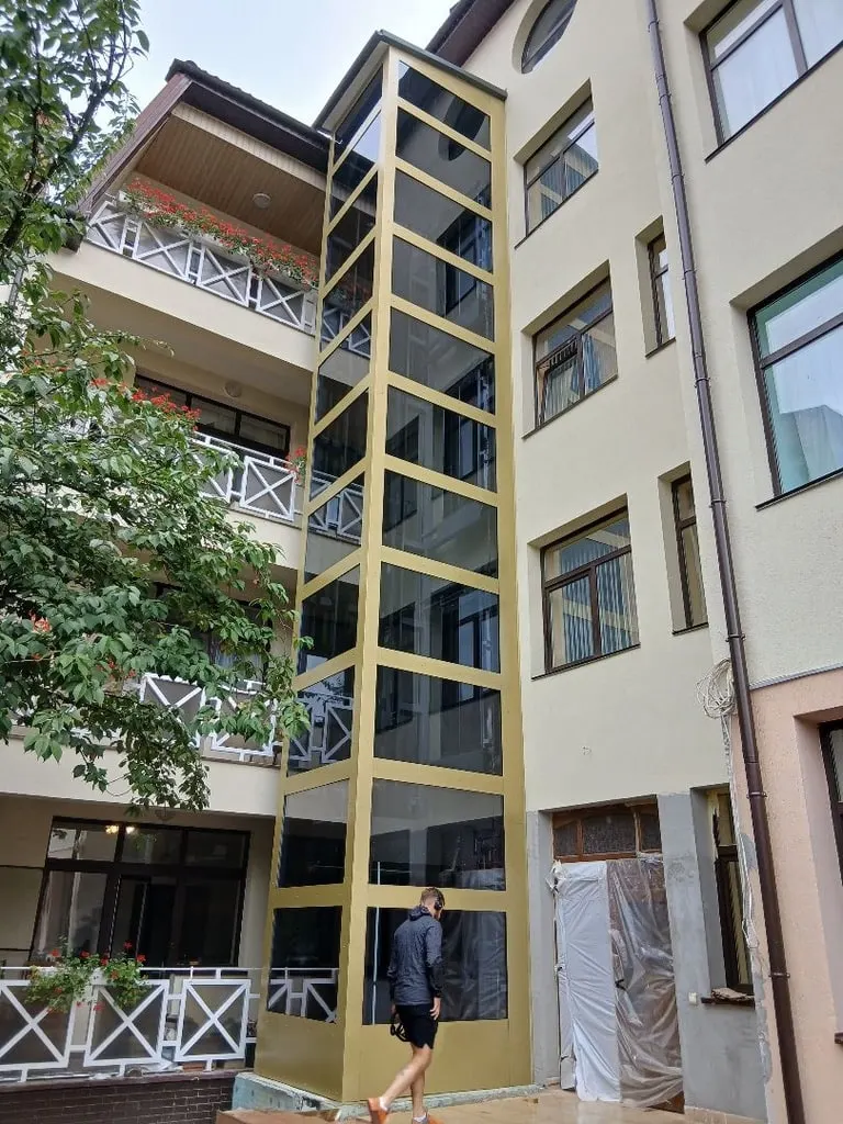 Панорамна ліфтова шахта на фасаді житлового будинку у внутрішньому дворі